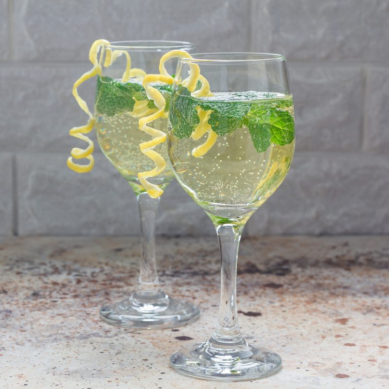 spritzer-cocktail-with-white-wine-mint-and-ice-decorated-with-spiral-lemon-zest-square-format.jpg